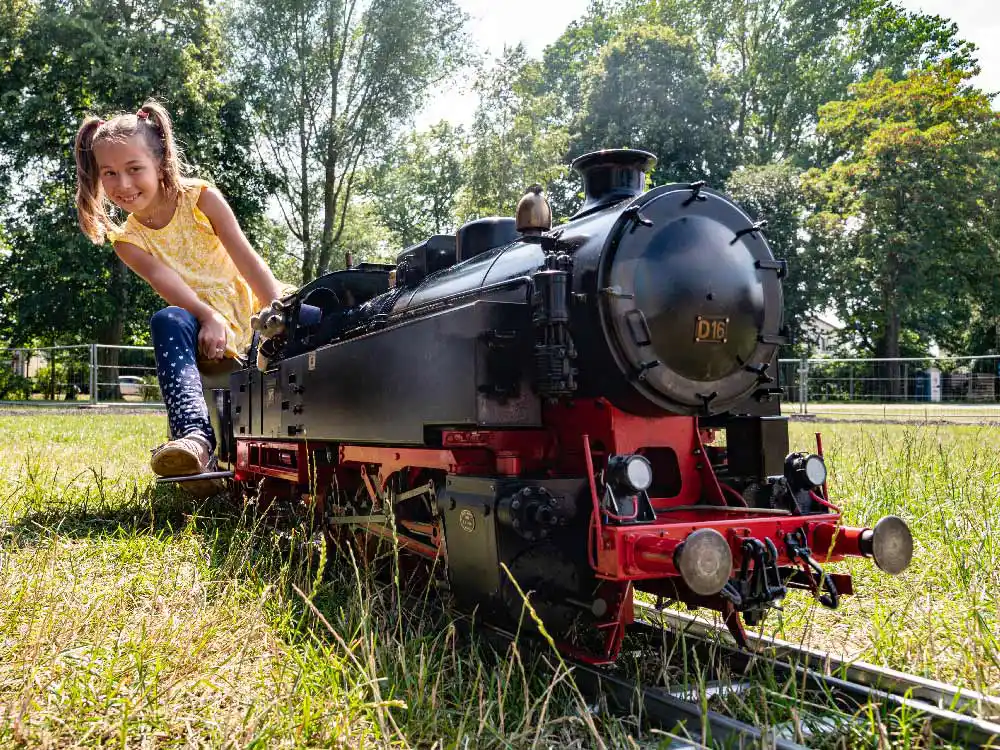 Kind sitzt lachend auf einer Echtdampf-Lok der Modelleisenbahn Usedom